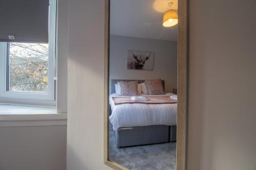 a mirror reflection of a bed in a bedroom at Kerr Apartment-Spacious 4-Bed Flat in Hamilton, Close to Glasgow in Cadzow