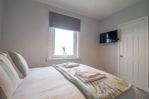 a bedroom with a bed with two towels on it at Kerr Apartment-Spacious 4-Bed Flat in Hamilton, Close to Glasgow in Cadzow