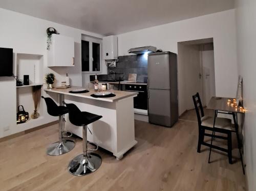 La cuisine est équipée d'un comptoir, de chaises et d'un réfrigérateur. dans l'établissement Zenappart - Charmant appartement P2 proche centre ville, à Nîmes