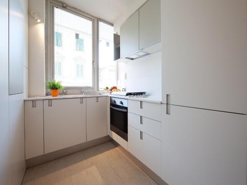 a white kitchen with white cabinets and a window at La Farina Apartments in Florence