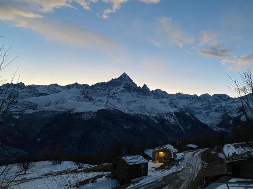 a snow covered mountain with a house in the foreground at BAITA GHITIN in Ostana
