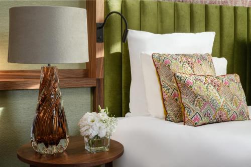 a bed with a lamp and flowers on a table at Hôtel Métropole Genève in Geneva