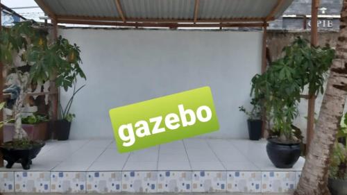 a green sign on a wall with potted plants at Yetelu Guest House in Bontang