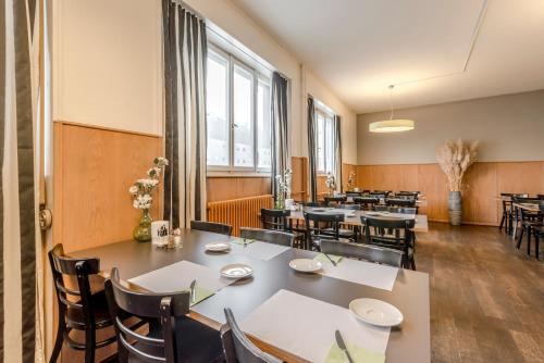 a dining room with tables and chairs and windows at Boutique Hotel KARL in Luzern