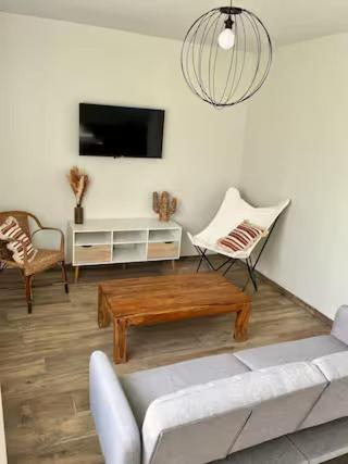 un salon avec un canapé, une table et une télévision dans l'établissement Chez Yvonne, à Neuf-Église