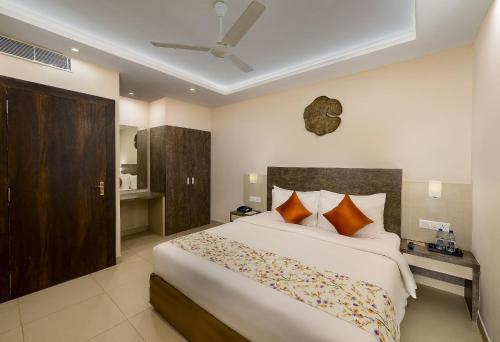 a bedroom with a large white bed with orange pillows at Hotel White Rose IGI Airport in New Delhi