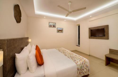 a bedroom with a white bed and a tv at Hotel White Rose IGI Airport in New Delhi