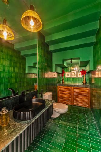 a green bathroom with a toilet and a sink at La Masillia, 2 BHK with Private Pool, 15 mins from Morjim Beach, Wifi, Peaceful location, Kitchen, Security, Patio in Siolim