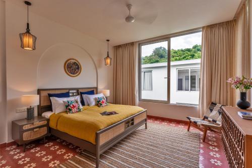 a bedroom with a bed and a large window at La Masillia, 2 BHK with Private Pool, 15 mins from Morjim Beach, Wifi, Peaceful location, Kitchen, Security, Patio in Siolim