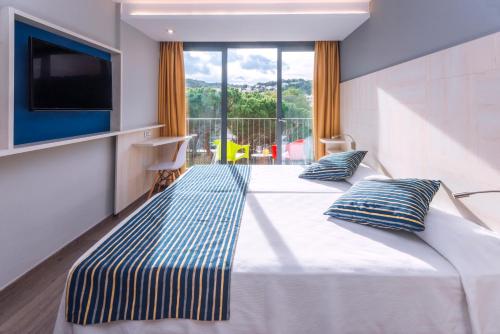a hotel room with two beds and a tv at GHT Sa Riera in Tossa de Mar