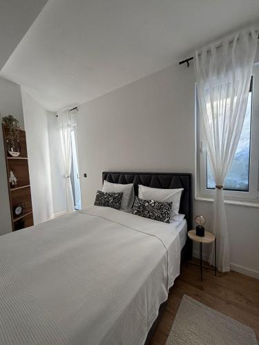 a white bedroom with a large bed with windows at Harmony Peak Jahorina in Jahorina