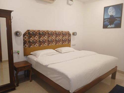 a bed with white sheets and a headboard in a room at Vintage Luxury Bungalow in Puducherry