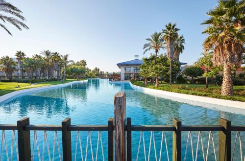 a swimming pool with a fence and palm trees at PortAventura Hotel Caribe - Includes unlimited access to PortAventura Park & 1 access to Ferrari Land in Salou