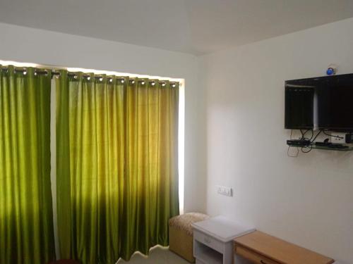 a room with a green curtain and a television at Ooty Blue Mountain Villa Thalayathimund in Ooty