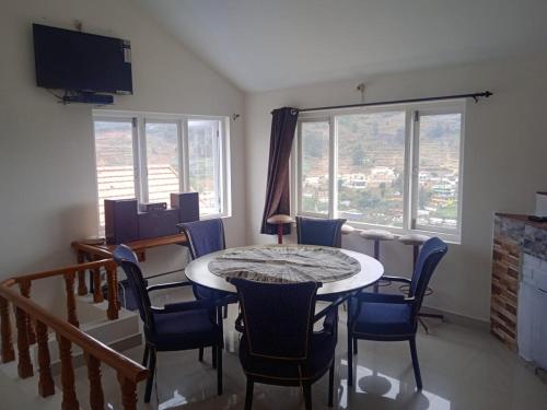 a dining room with a table and chairs and a tv at Ooty Blue Mountain Villa Thalayathimund in Ooty