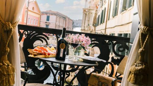 a table with a bottle of wine and fruit on a balcony at Hotel Al Ponte Dei Sospiri in Venice