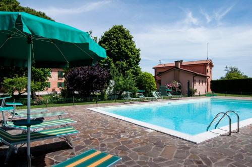 a swimming pool with lounge chairs and an umbrella at Agriturismo Santa Barbara in Mira