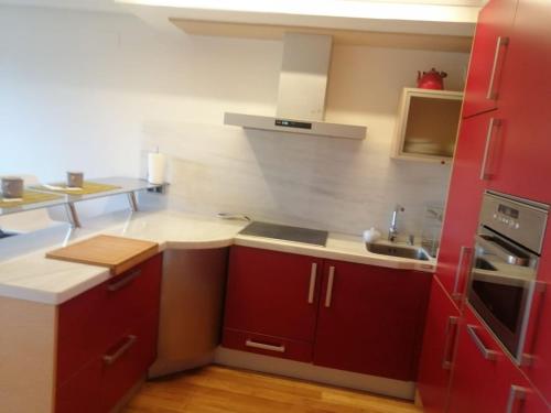 a kitchen with red cabinets and a sink at El apartamento de Noe in Berrón