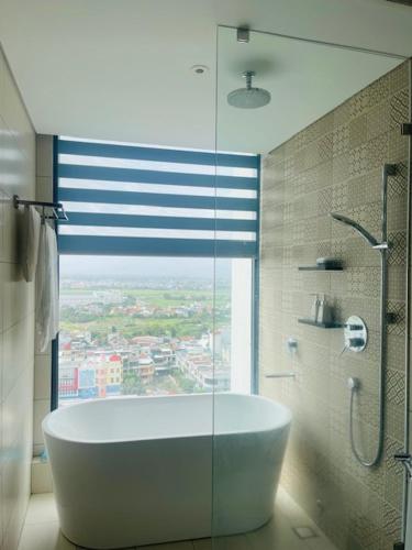 a bathroom with a tub and a shower with a window at Sea La Vie Tuy Hoa Beachside Studio in Tuy Hoa