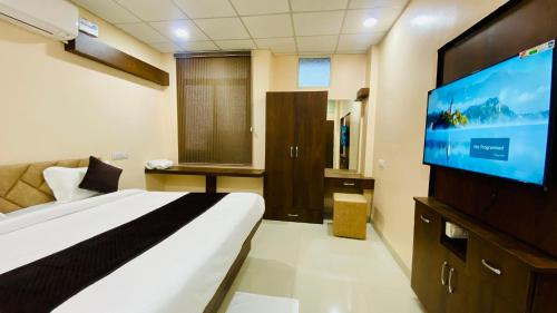 a hotel room with a bed and a flat screen tv at Stay10 B&M LUXURY ACCOMDATION in Indore