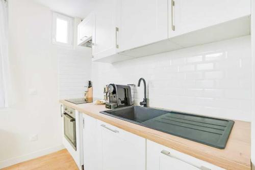 - une cuisine avec un évier et des placards blancs dans l'établissement Cosy Apt - 2P - République - Marais, à Paris