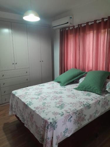 1 dormitorio con cama con almohadas verdes y cortina roja en Casa do arco-íris, en Florianópolis