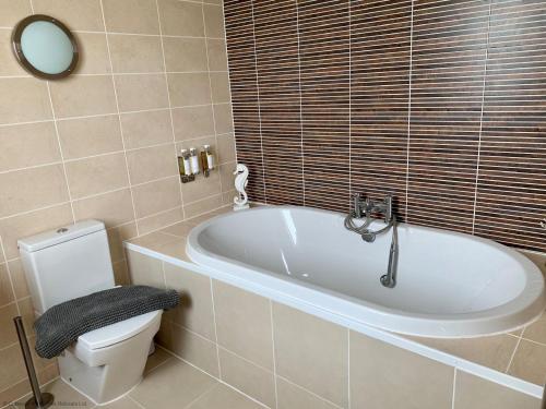 ein Badezimmer mit einer weißen Badewanne und einem WC in der Unterkunft Libelle Lodge in South Cerney