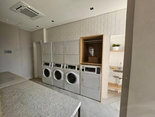 eine Waschküche mit drei Waschmaschinen und einem Waschbecken in der Unterkunft Apto novo e moderno - 5 min do Allianz parque in São Paulo