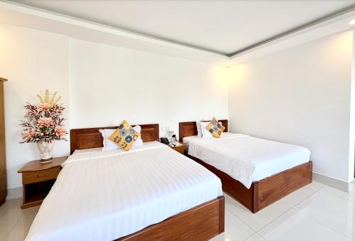 a bedroom with two beds and a vase of flowers at Palace Hotel - Rạch Giá in Rach Gia