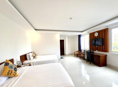 a hotel room with two beds and a desk at Palace Hotel - Rạch Giá in Rach Gia