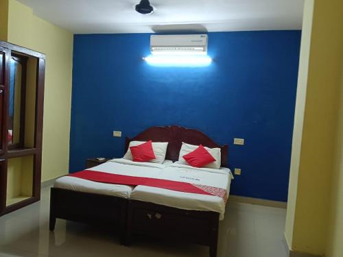 a bedroom with a blue wall and a bed with red pillows at Royal Residency in Trivandrum