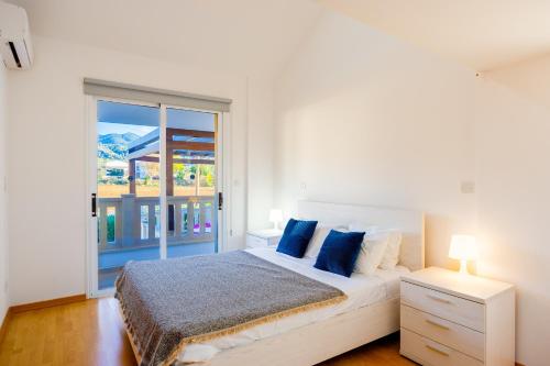 a bedroom with a bed with blue pillows and a window at Villa Bella Ena in Nea Dimmata