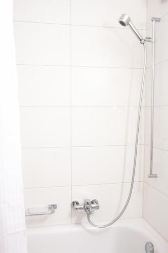 a shower in a white bathroom with a tub at Armotti Weissenbühl 1 Bedroom Apartment in Bern
