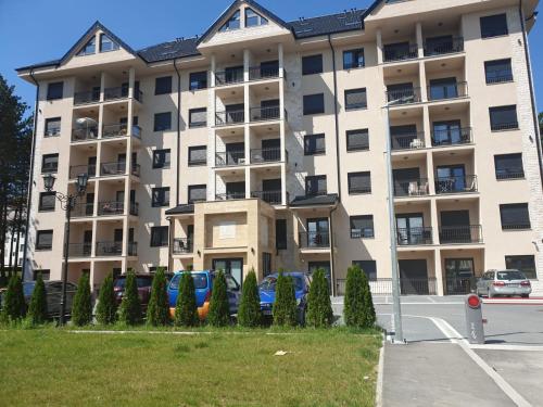 an apartment building with cars parked in front of it at Vila Elsa in Zlatibor