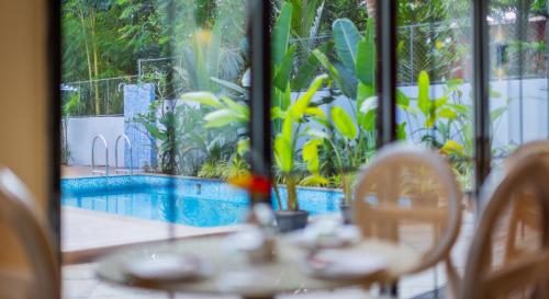 a table with chairs and a pool outside a window at Goan Bliss in Varca