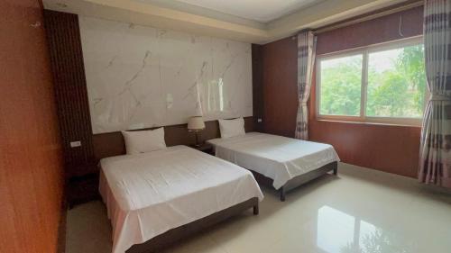 a bedroom with two beds and a window at Khách sạn Vĩnh Lộc in Lao Cai