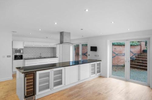 a kitchen with white cabinets and a black counter top at 5 bed house with hot tub in Powick
