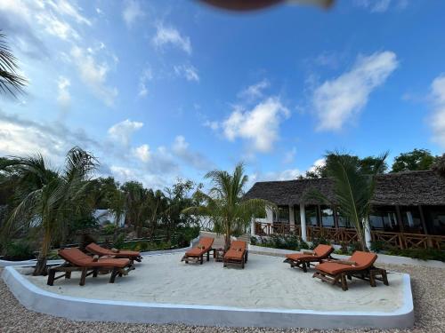 a group of lounge chairs sitting on a beach at M&M Villas Zanzibar in Kidoti