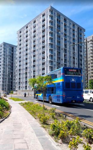 a blue bus driving down a street in front of a tall building at Clove Beach Hulhumale in Male City