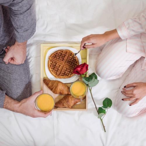 a group of people laying on a bed with a waffle and drinks at Swiss Flora Royal Hotel Riyadh in Riyadh