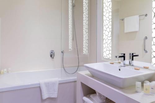 a white bathroom with a sink and a shower at N’vY Manotel in Geneva