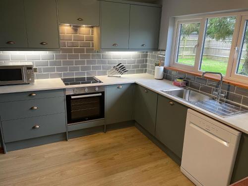 a kitchen with green cabinets and a sink at Landews Meadow Cottages in Badlesmere