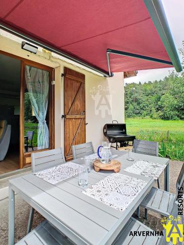une table avec un parasol devant une maison dans l'établissement Villa Clara, à Murol