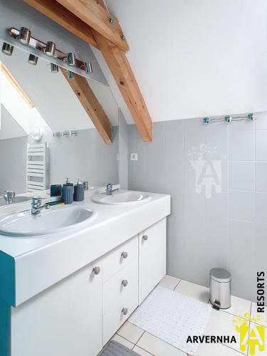 une salle de bain blanche avec deux lavabos et une douche dans l'établissement Villa Clara, à Murol