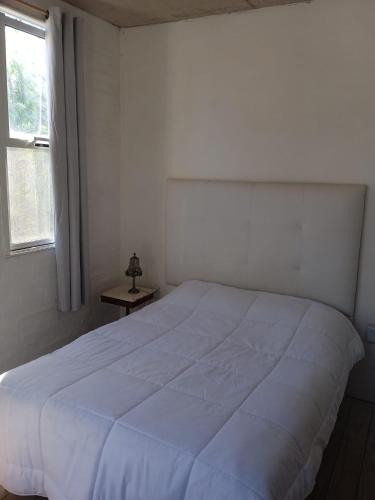 un letto bianco in una camera da letto con una finestra di Devoto Piriapolis a Piriápolis