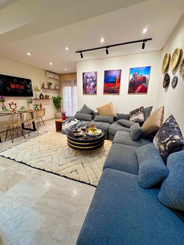 ein großes Wohnzimmer mit blauen Sofas und einem Tisch in der Unterkunft Appartement luxe au cœur de Marrakech in Marrakesch