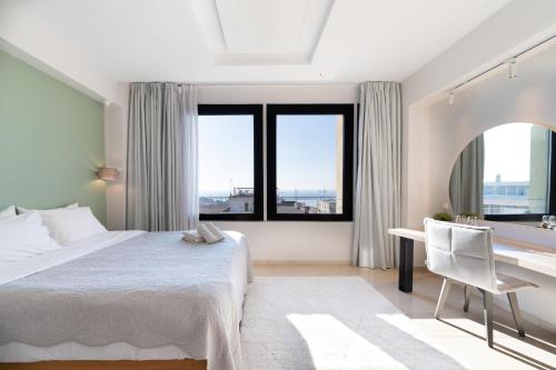 a bedroom with a bed and a desk and windows at Sea & the City in Thessaloniki
