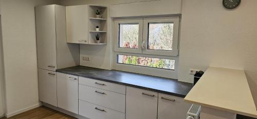 a kitchen with white cabinets and two windows at Ferienwohnung Schuller in Gottmadingen