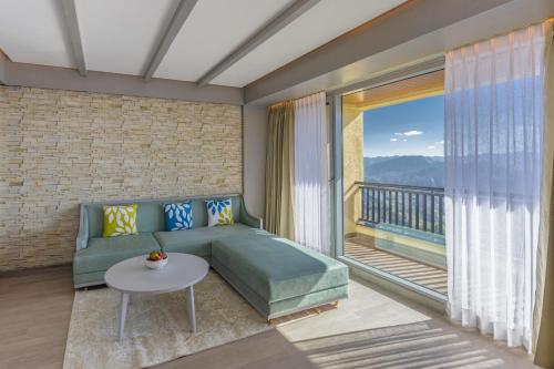 a living room with a couch and a balcony at dusitD2 Fagu, Shimla in Shimla