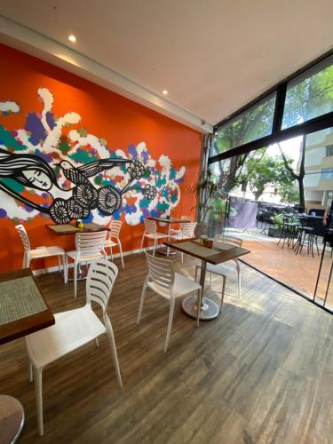 a restaurant with tables and chairs and a colorful wall at Royal Design Savassi Hotel in Belo Horizonte